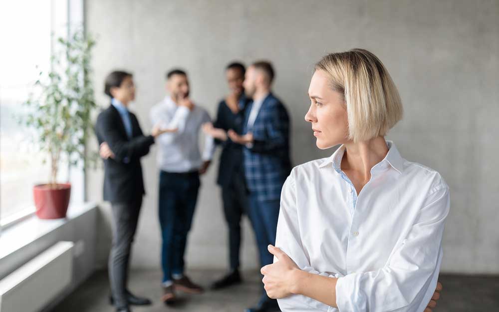 A woman in front of a group, which is focused elsewhere and not acknowledging her.