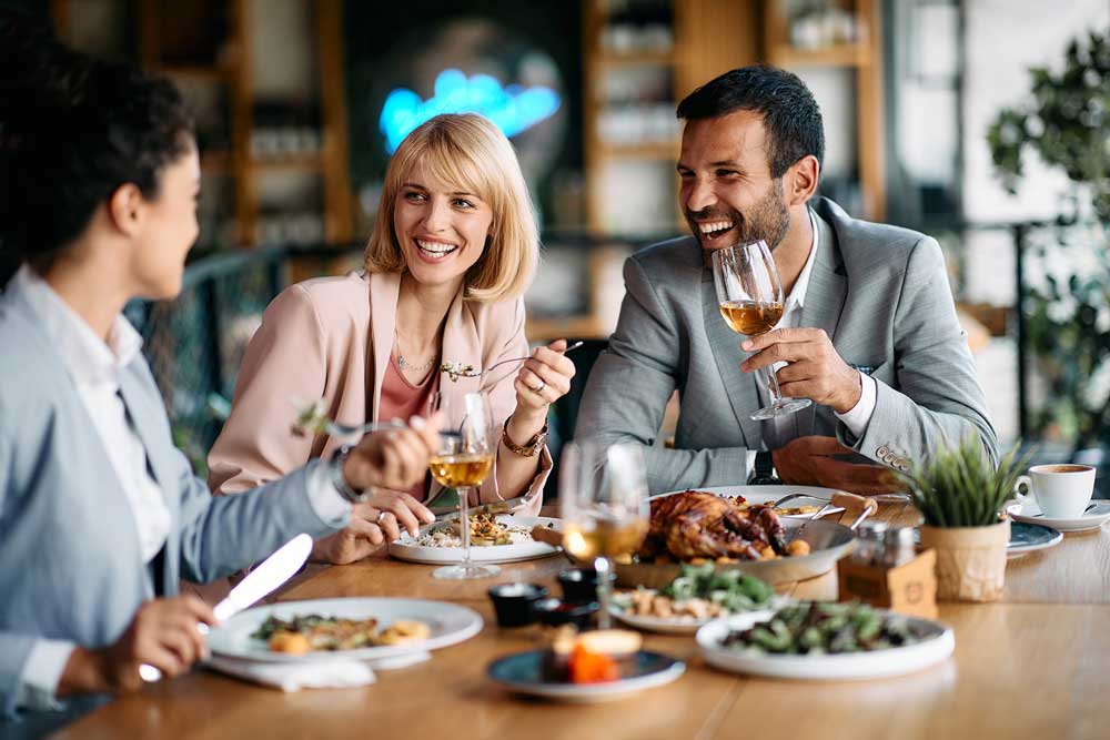 A diverse group of friends gathered around a table, enjoying a meal together.