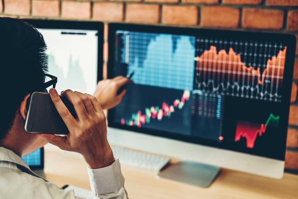 A man studies stock market graphs on his computer, reflecting on the complexities of insider trading.