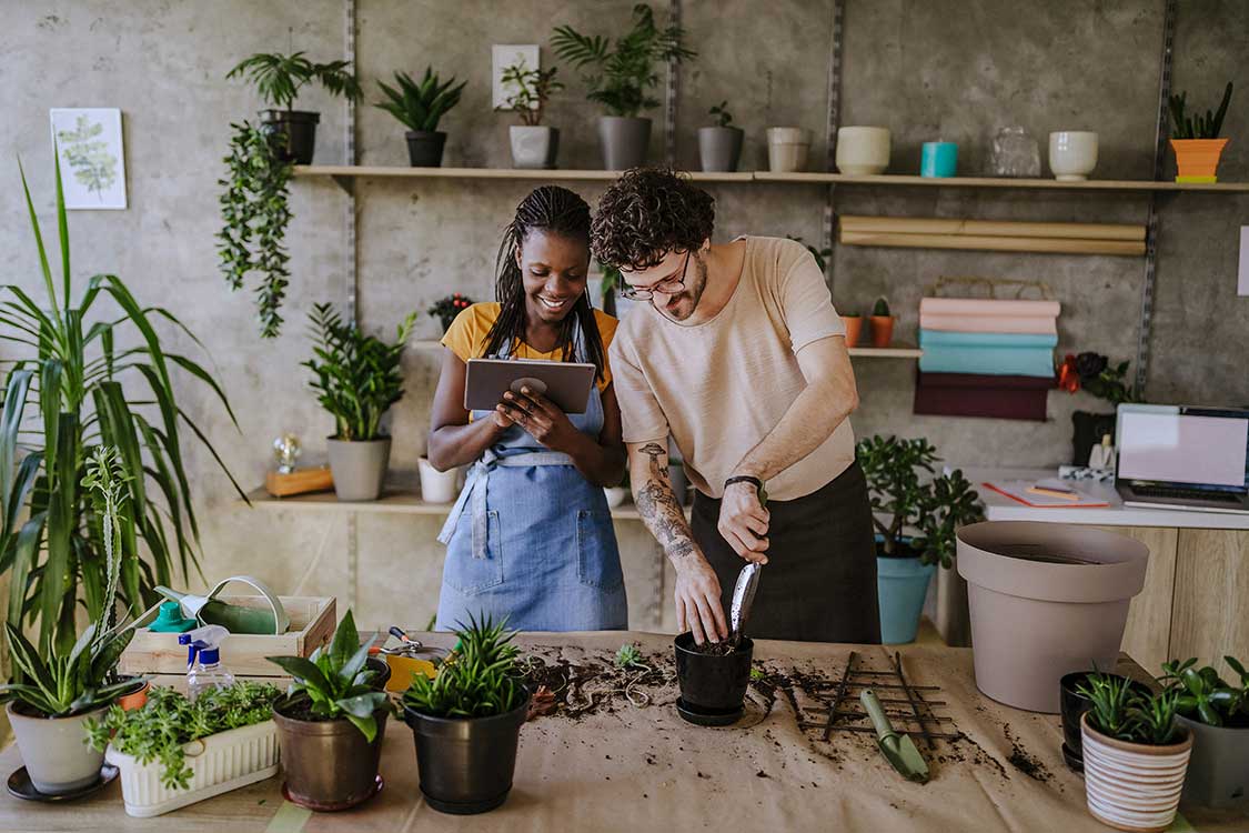 A man and a woman with a tablet, sorrounded by plants