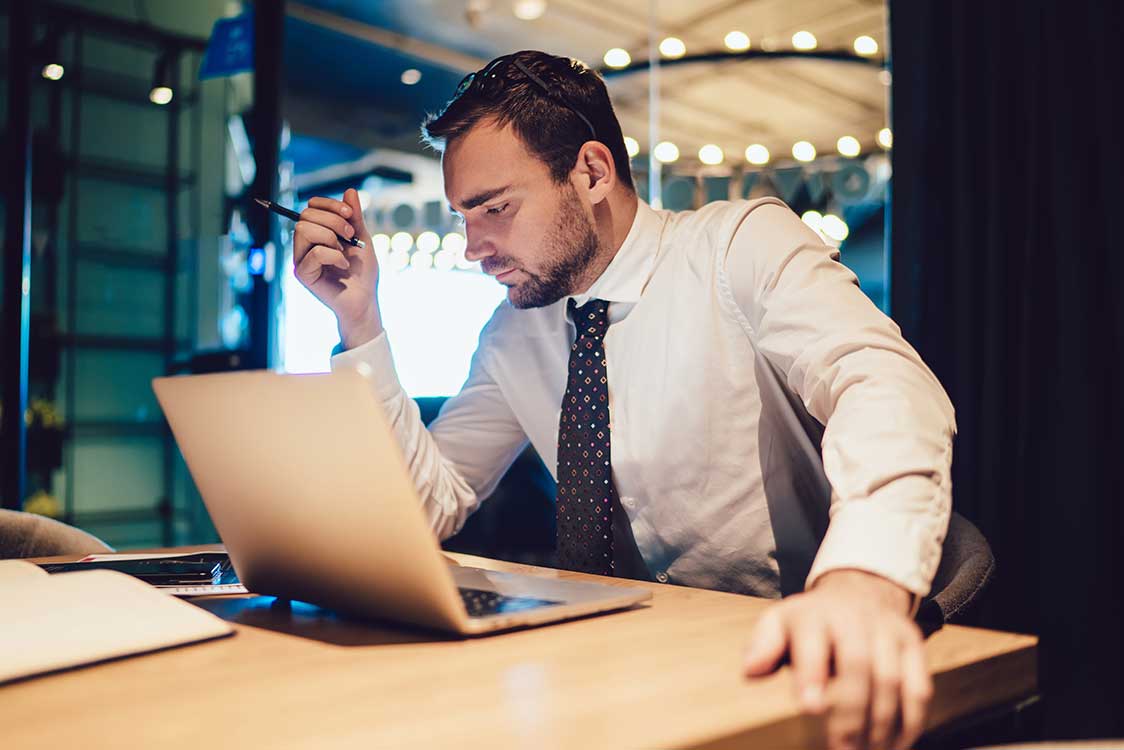 A man in formal attire, working on a laptop computer