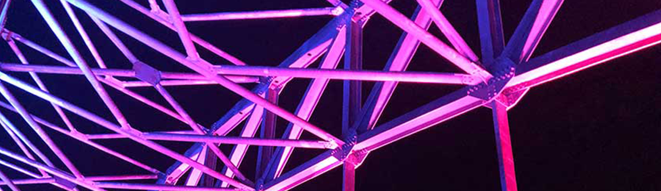A bridge illuminated by vibrant pink and blue lights