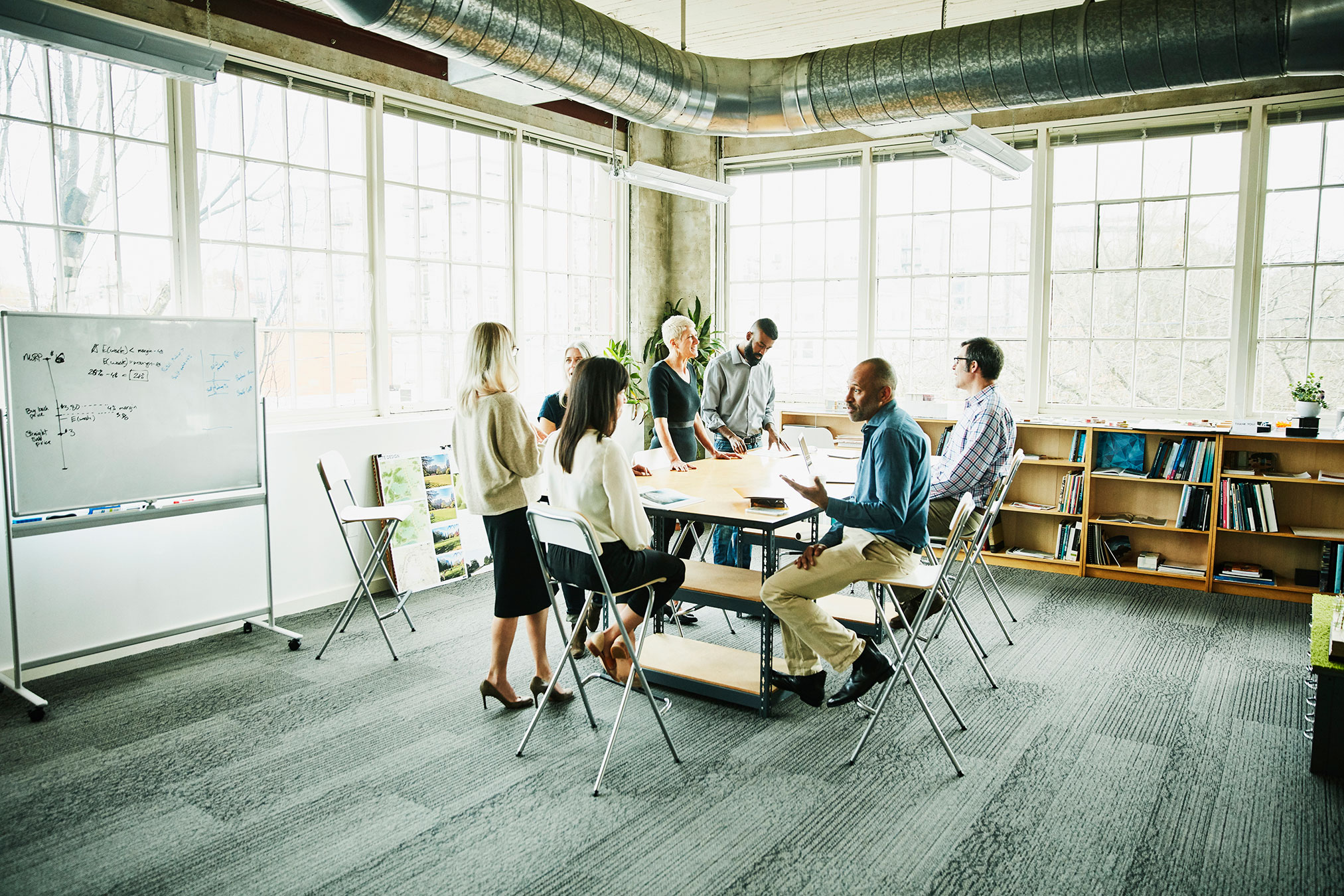 A diverse team of collegues engaged in a meeting, discussing ideas and collaborating at an office table