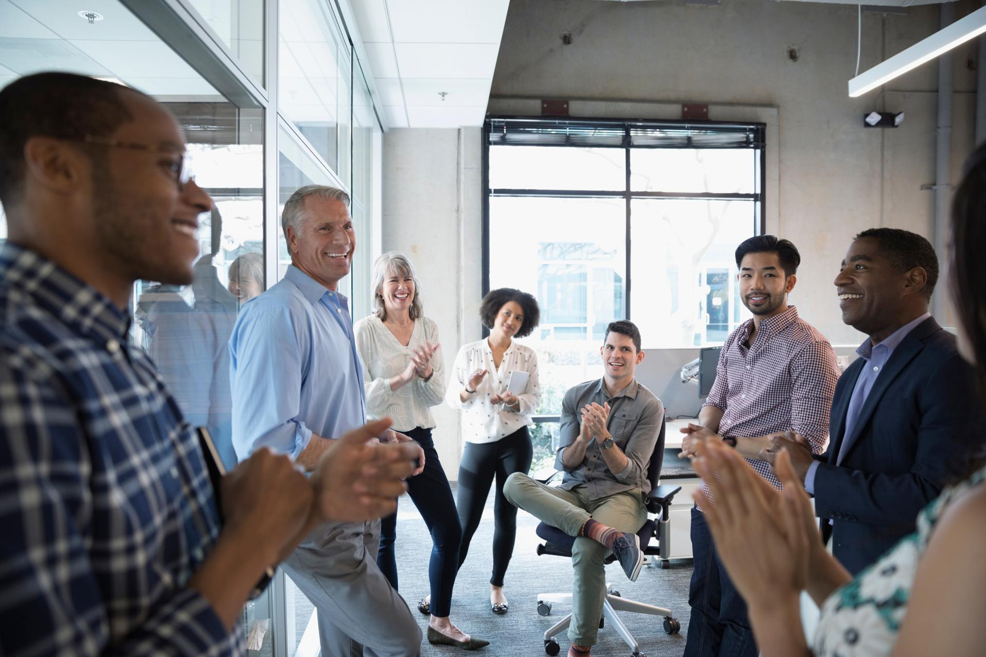 A group of collegues applauding in a office, showing appreciation and support for an achievement